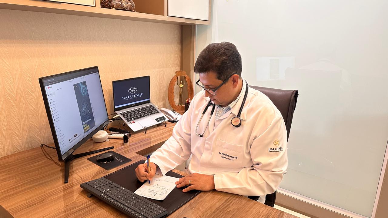 Dr. Abel Dib Rayashi escrevendo uma prescrição.